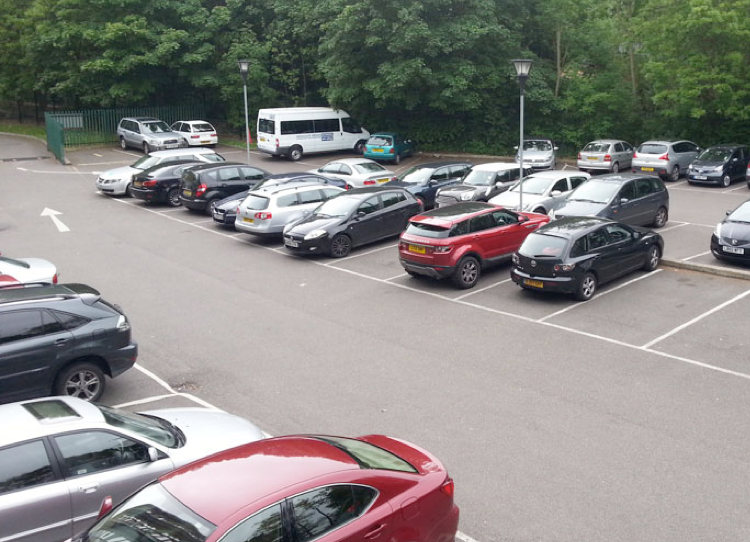 A car park with marked bays, lined with trees