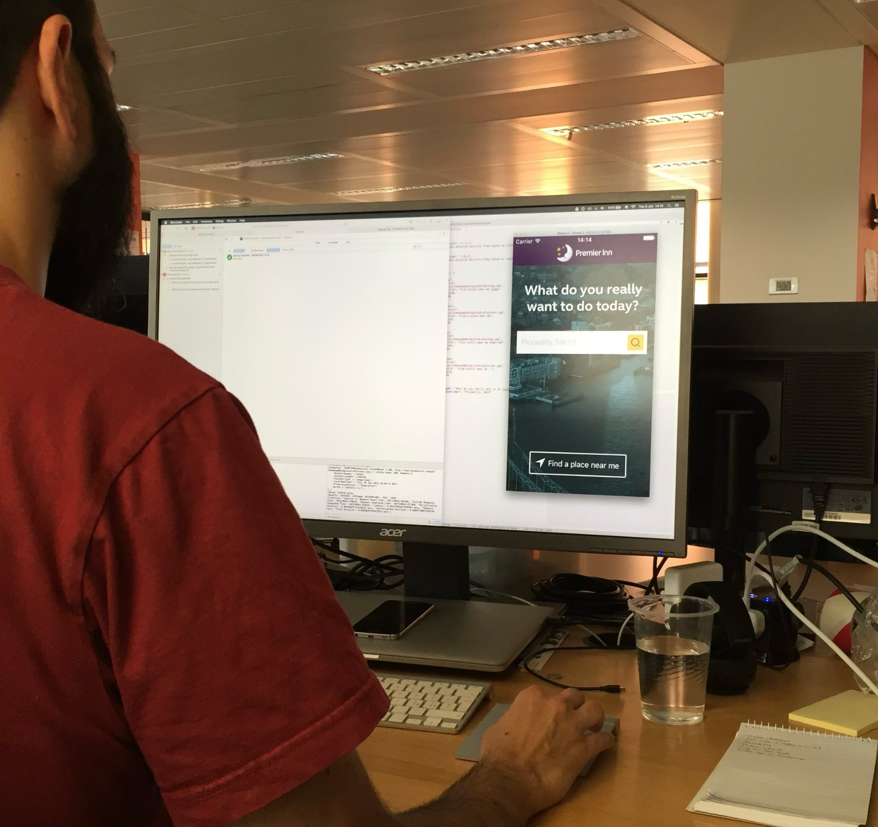 An iOS developer at his desk working on the app's landing screen in the simulator